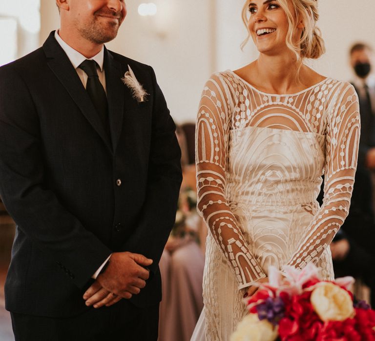 Bride in long sleeve wedding dress smiling during the wedding ceremony 