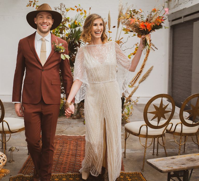 Couple holding hands walking down a persian rug wedding aisle