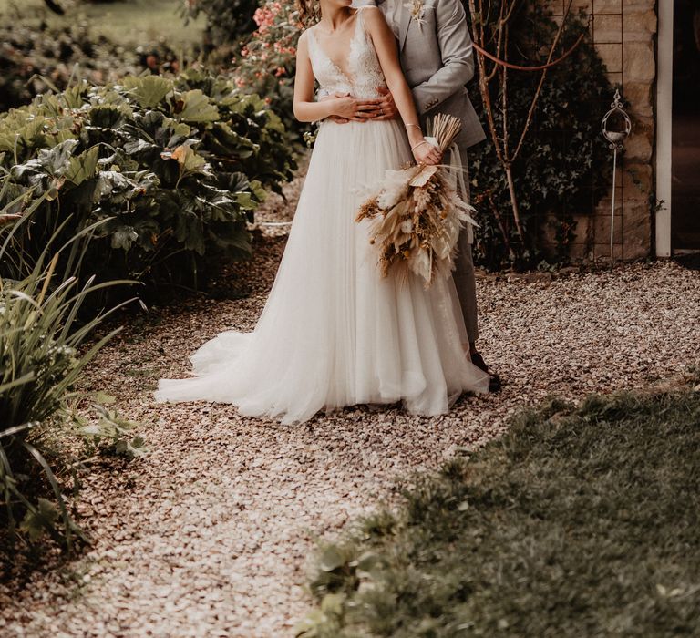 Bride with dried flower wedding bouquet hugging groom