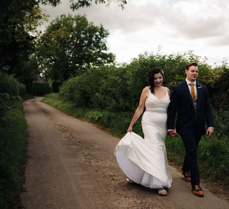 Bride & groom walk through the countryside hand in hand