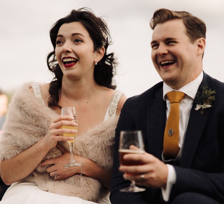 Bride & groom sat together with bride in fur stole 