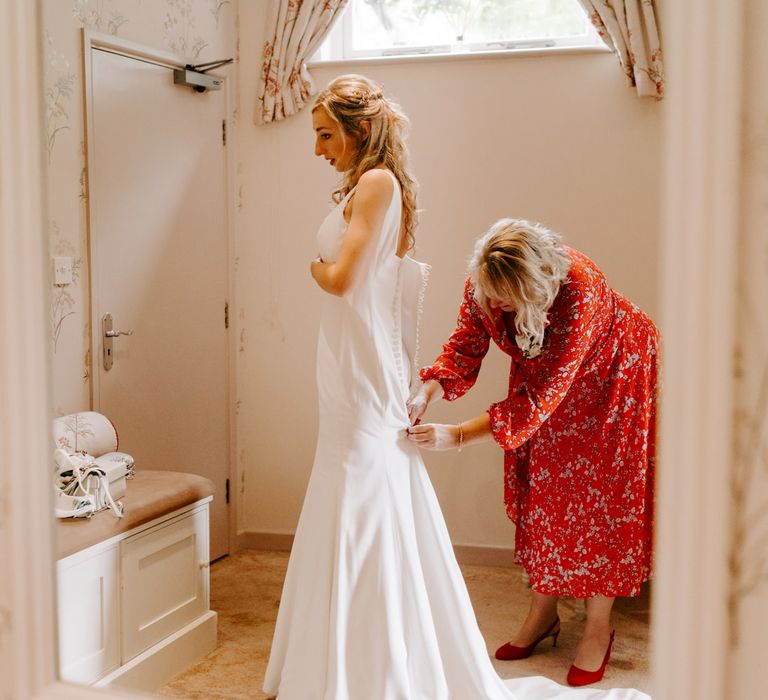 Bride on the wedding morning putting her Suzanne Neville wedding dress on 