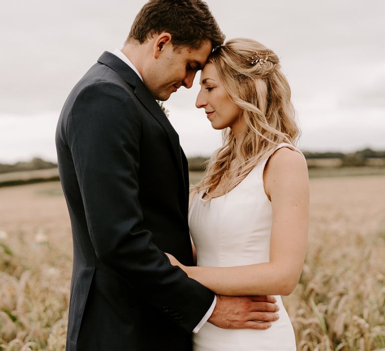 Bride and groom embracing in a field by Sam Cook Photography 