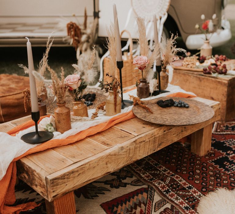 Low wooden table complete with black candlestick holders 