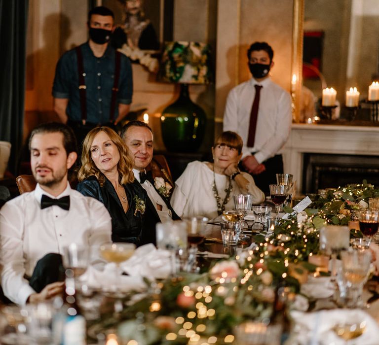 Wedding guests sat at wedding table with festive fairy lights