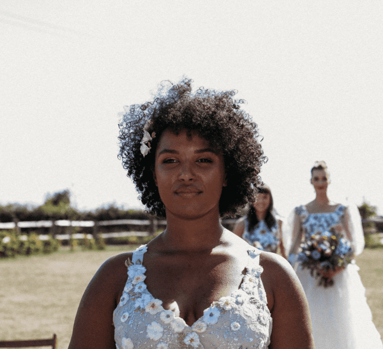 A Bride wears her short afro hair loose as she walks holding a bouquet