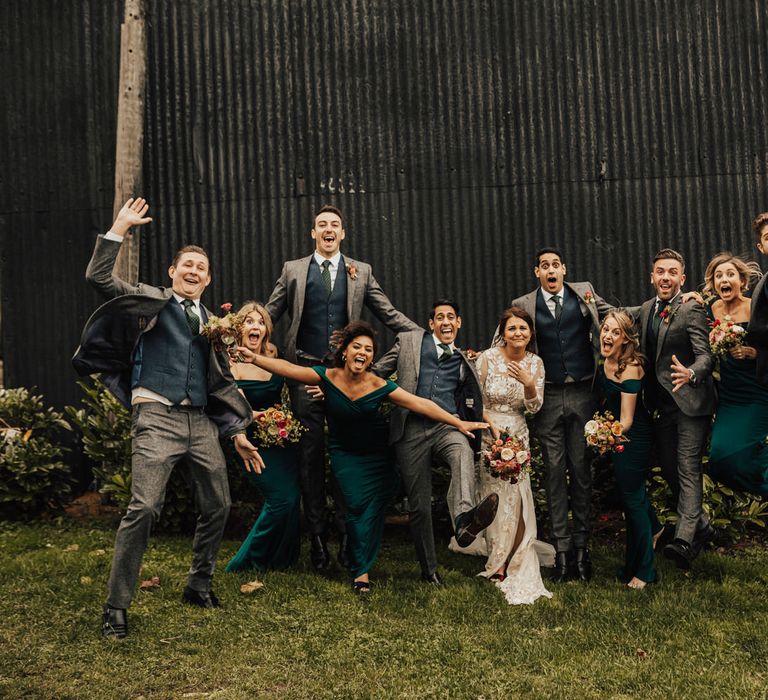 Fun wedding party portrait by Darina Stoda Photography with the Groomsmen in grey wool suits, the bridesmaids in dark green off the shoulder dresses and the bride in lace Hermione de Paula wedding dress 