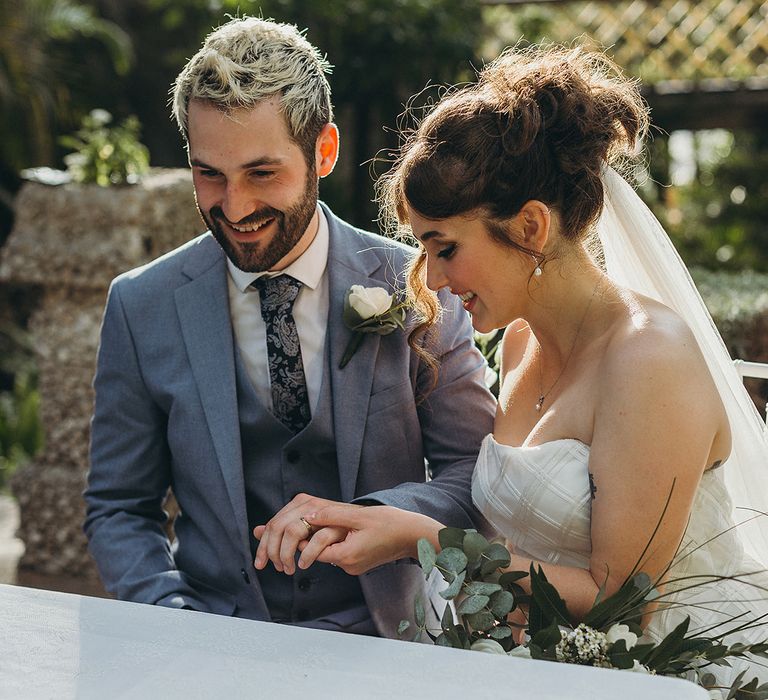 Bride in a strapless wedding dress looking at her grooms wedding band at their intimate elopement 