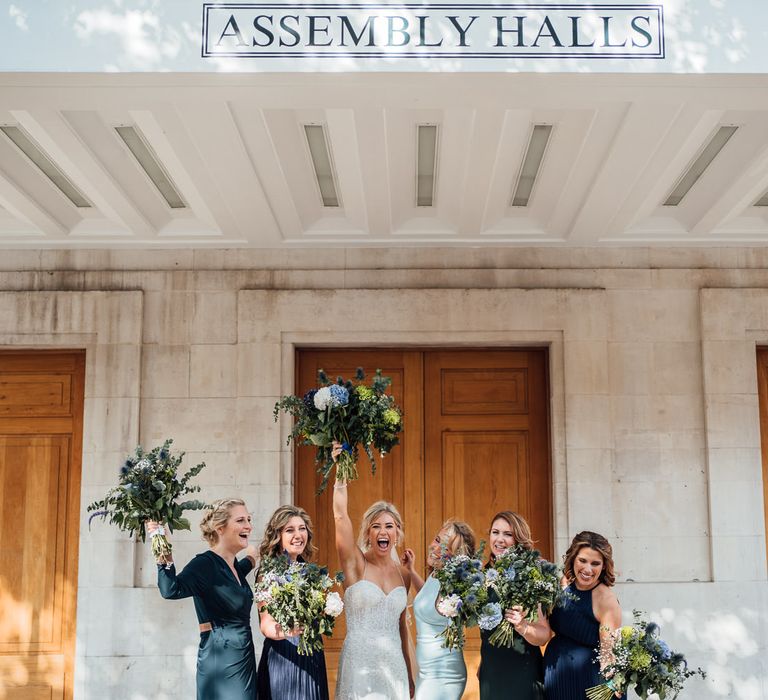 Bride celebrates with bridesmaids in blue dresses after wedding ceremony