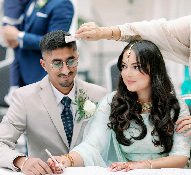 Mother of the bride swirling notes of money around the bride and groom to prevent dangers of the evil eye 