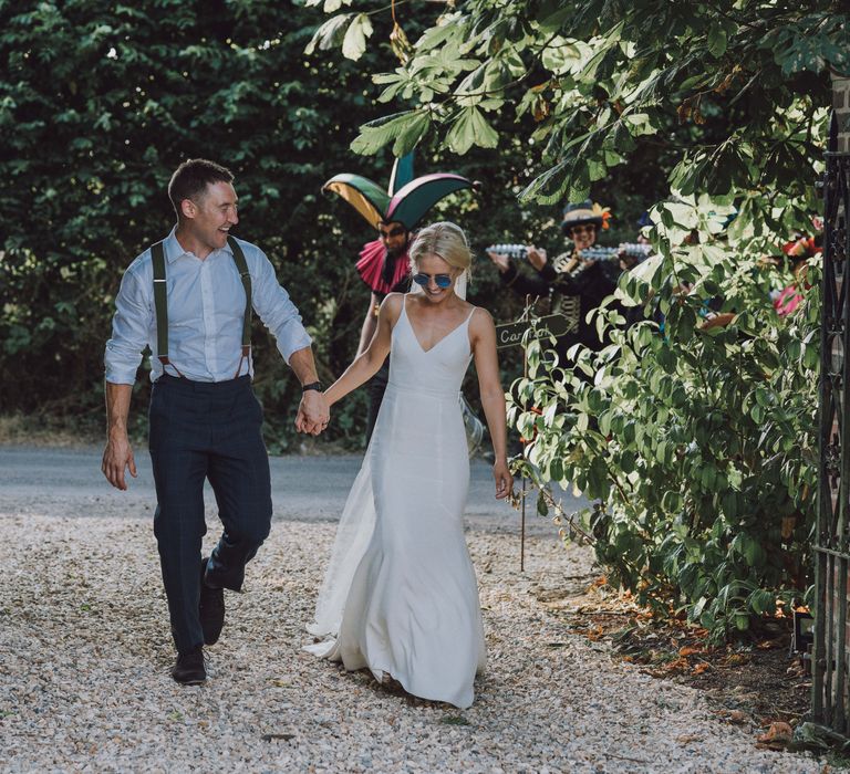 Bride & groom walk together hand in hand 