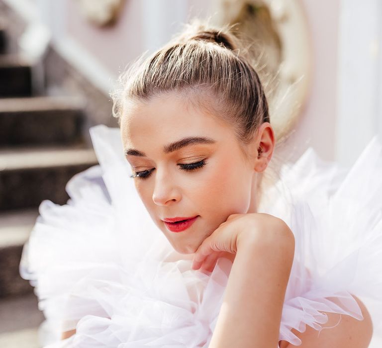 Bride in a ruffle wedding dress with sleek back hair gold eyeshadow and subtle pink lipstick 