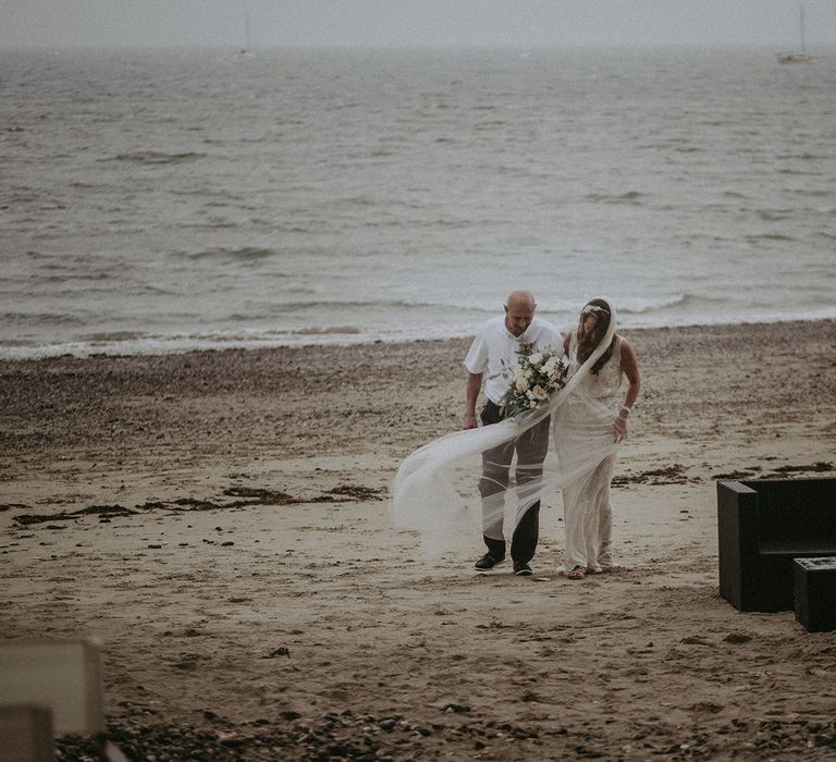 Bride & groom stand together on the beach on the day of their wedding