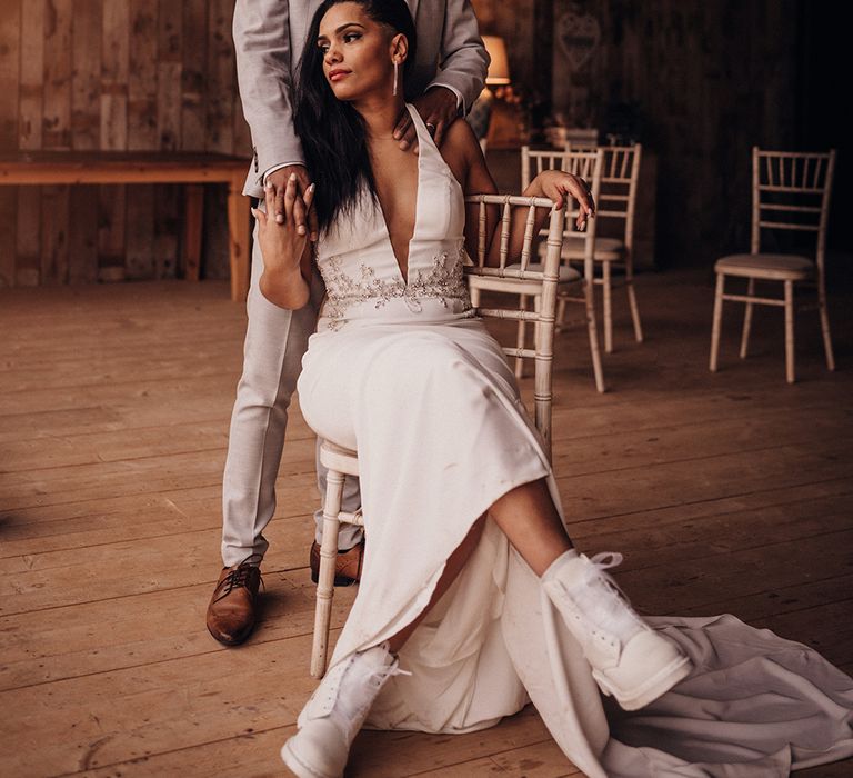 Bride sits down as groom stands behind her and places his hands on her shoulders