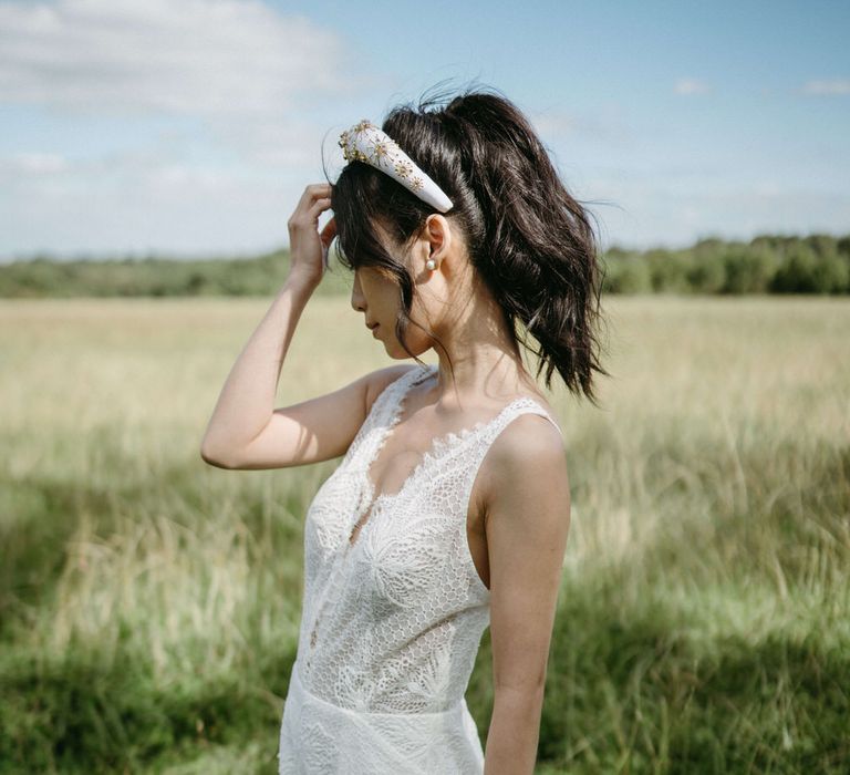 Bride wearing a lace wedding dress with plunge neckline and a white and gold beaded headband