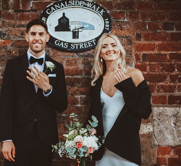 Bride and groom standing by the Canalside walk, Gas Street sign showing off their wedding bands 