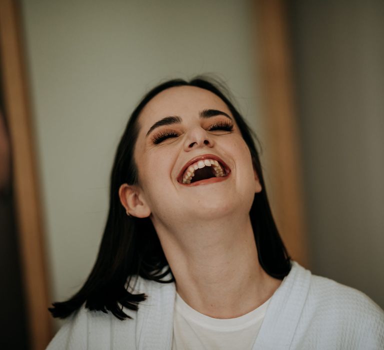 Bride on her wedding morning laughing with brown shimmering eyeshadow and long eyelashes 