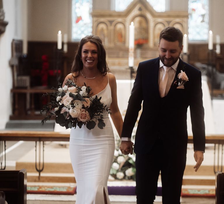 Bride and groom making their aisle descent at their church wedding