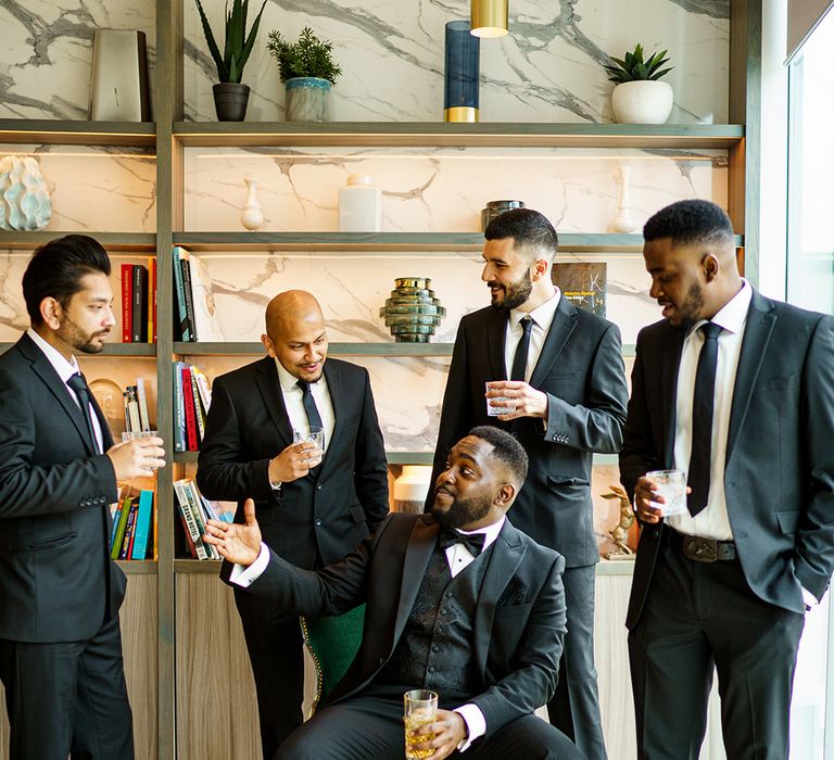 Groom stands with his ushers all wearing black suits 