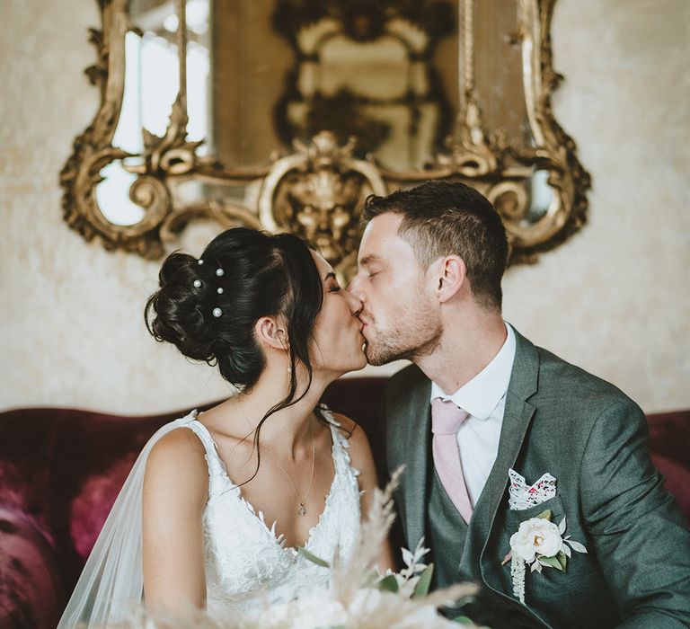 Bride & groom kiss in front of golden gilded frame on their wedding day