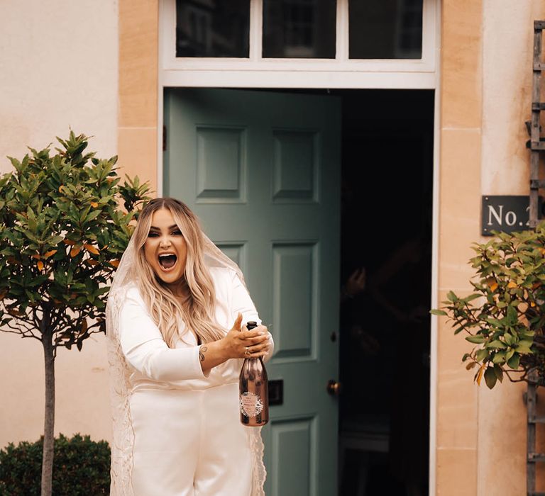 Blonde bride pops champagne outdoors on her wedding day