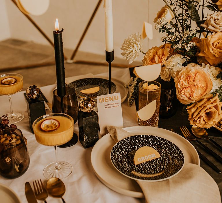 Black side plates, candlestick holders and taper candles for contemporary wedding with yellow, orange and gold accents 