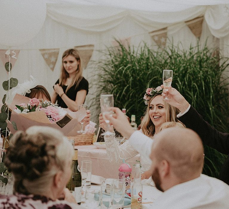 Bride and groom raising their glasses during their back garden marquee wedding reception 