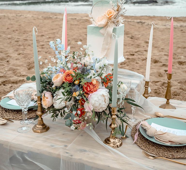 Pastel wedding inspiration by the sea with square two tier wedding cake, flowers and candles 