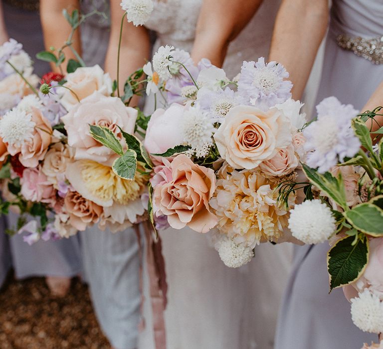 Bridesmaids hold pastel coloured bouquets