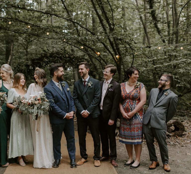 Bride & groom stand with their wedding party on their wedding day outdoors in the woodlands