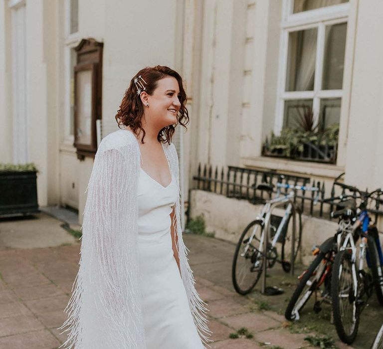 Bride walks to ceremony wearing Halfpenny London tassel cape