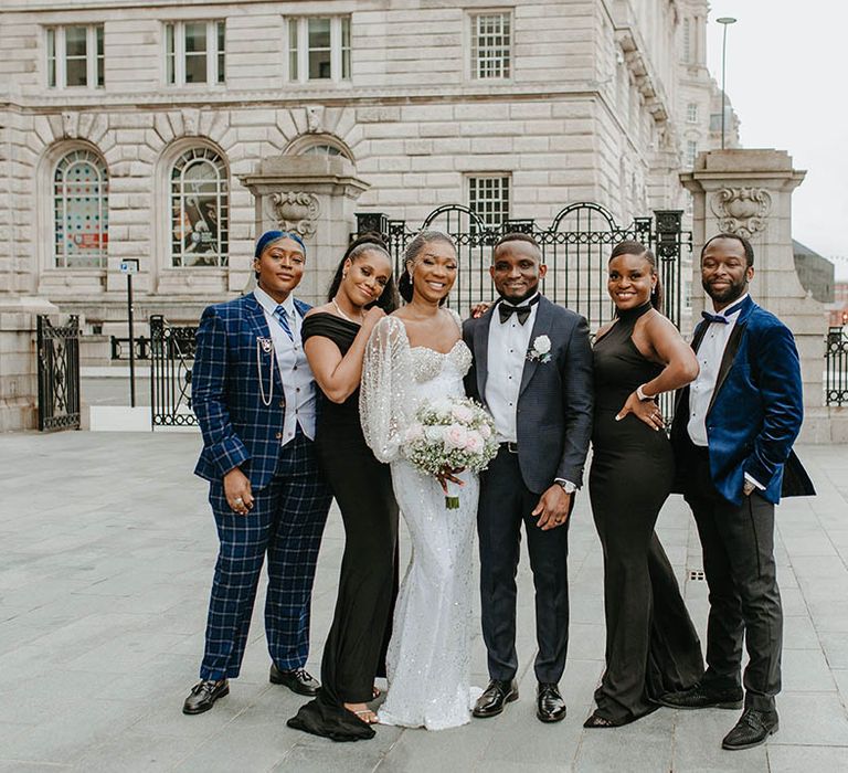 Bride & groom stand with their wedding party outdoors on their wedding day