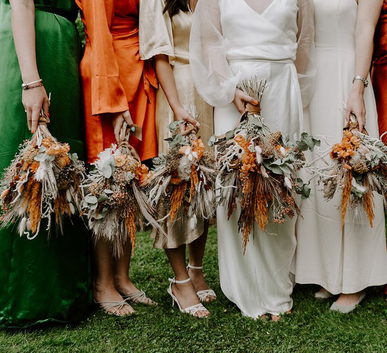 Bridal party holding dried flower bouquets with orange and neutral grasses, bunny ears and foliage 