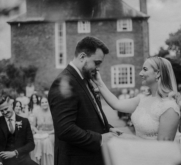 Outdoor wedding ceremony at Dewsall Court with bride in a Jesus Piero wedding dress embracing her grooms face 