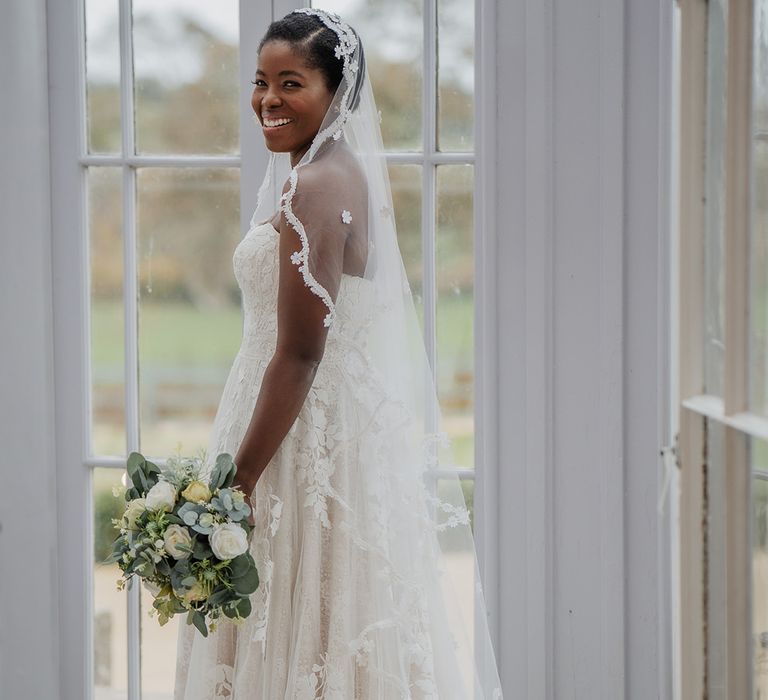 Stunning Black Bride in sweetheart neckline and lace edge wedding veil holds summer boutique 