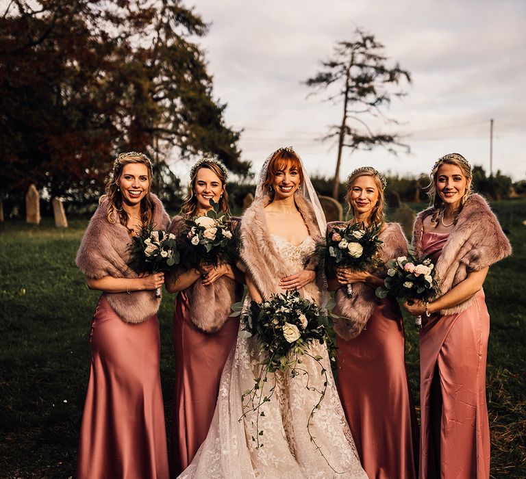 Pink bridesmaid dresses with faux fur wraps at winter wedding