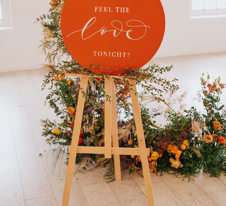 Circle "can You feel the love tonight?" golden wedding sign on a wooden easel 