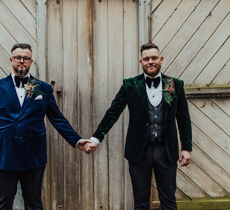 Grooms in blue and green velvet suit jackets with matching black bow ties and large buttonholes with a peacock feather 