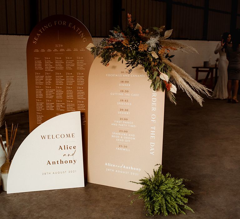 Orange, peach and white wedding signs with welcome, seating and order of the day signs and dried flower arrangements