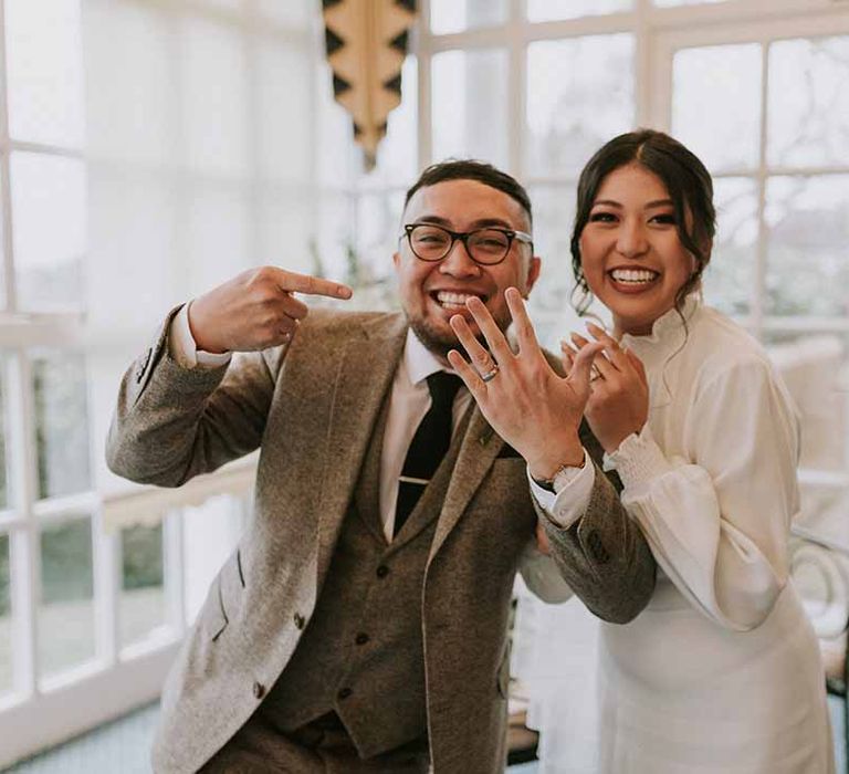 Groom in Tru Clothing outfit pointing to wedding ring