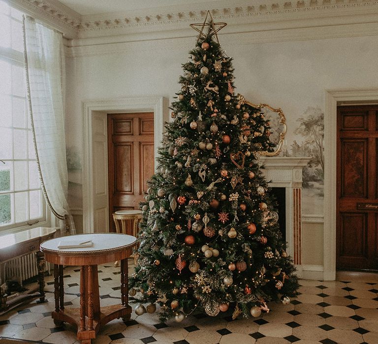 Large Christmas tree with warm-toned Christmas decorations at Hedsor House wedding