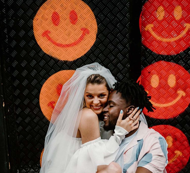 Fun urban elopement with bride in a short wedding dress and long veil and groom in a patterned shirt