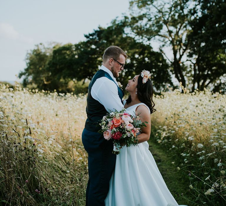 Bride and groom look into each other's eyes as they stand together in countryside at St Tewdrics House 