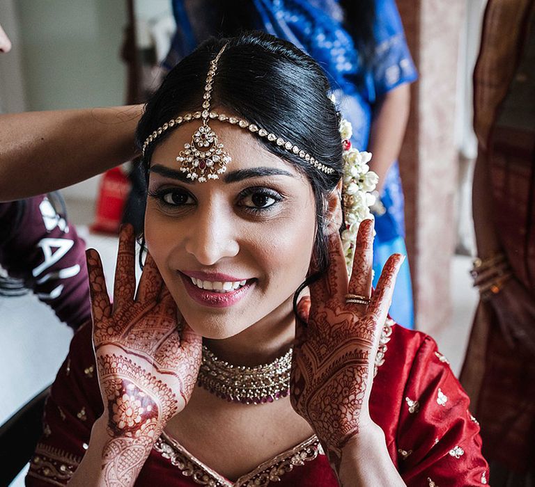 Bride with a smoky eye shows off her henna and stunning jewellery in red outfit 