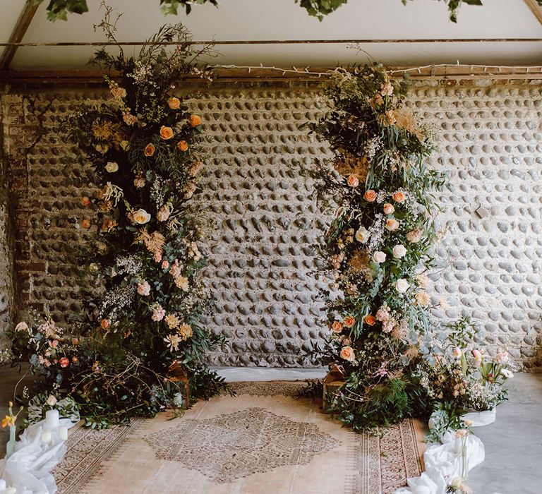 Wool rug and foliage and peach column wedding flowers decorating Montague Farm Hankham