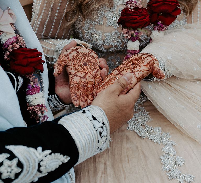 Groom holds brides hands who are covered in traditional Henna on her wedding day