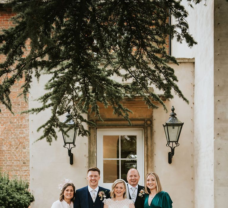 Bride & groom stand with family on their wedding day outdoors of Aswarby Rectory 