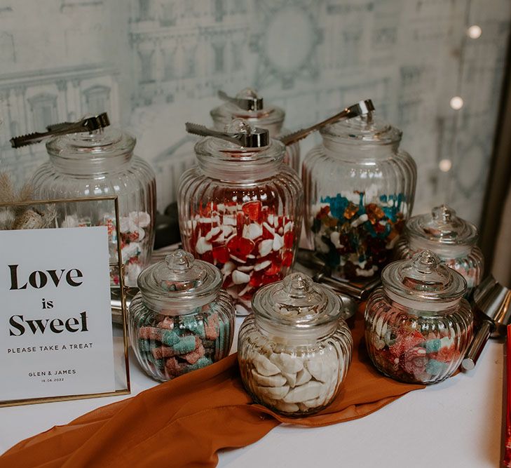 Sweets table complete with orange table runner and jars  full of sweets 