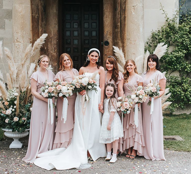 Bridal party shot with bridesmaids in pink dresses and flower girl in a white frill polka dot dress 