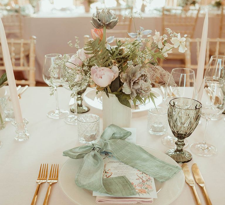 Pretty pastel wedding table setting with a pink and green colour scheme and copper cutlery with a floral menu card 